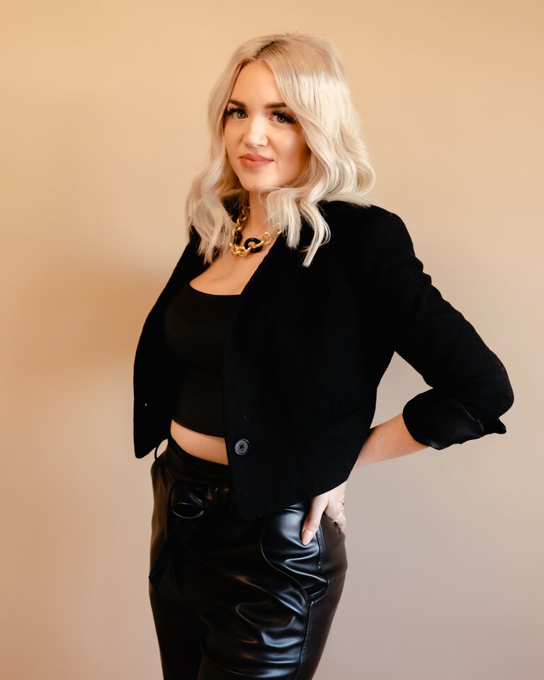 Rachel Hope in a black jacket against a warm studio backdrop
